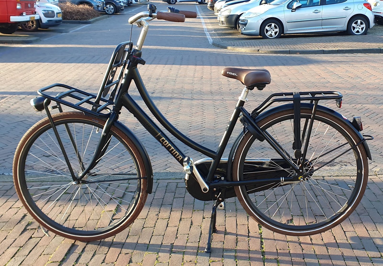 Zwarte Cortina-stadsfiets met voor- en achterdrager